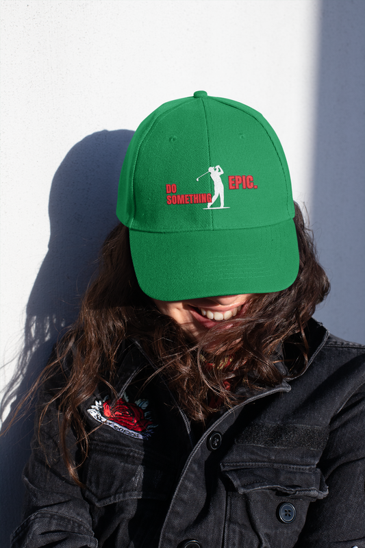 Person wearing a green cap with an embroidered Golfer logo and text Do Something Epic, sitting against a plain background